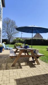 a picnic table with an umbrella on a patio at Ty Maen - Étage avec chambre, coin salon, toilettes et salle de bain in Erdeven