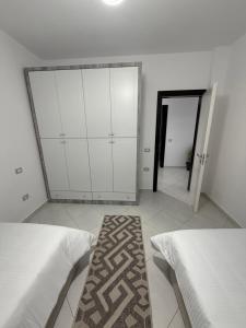 a bedroom with two beds and a closet and a rug at Villa Kokoneshi in Divjakë