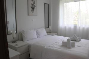 a bedroom with a white bed with towels on it at Christiana's House in Artemida
