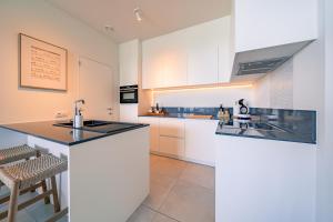 a kitchen with white cabinets and a black counter top at Top uitzicht luxe appartement DUNES met terras POOL & GYM in Ostend
