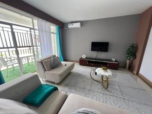 a living room with a couch and a tv at Magnólia Home in Muceque Baia