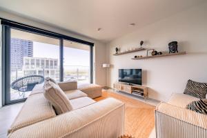 a living room with a couch and a tv at Top uitzicht luxe appartement DUNES met terras POOL & GYM in Ostend