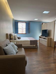 a bedroom with a bed and a couch and a tv at Pousada Contos de Minas in Mariana