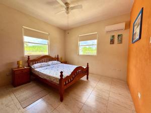 a bedroom with a wooden bed and two windows at Lailamar Villa, Ocean view, Pool & AC - Ground Floor in Saint Philip +15 photos