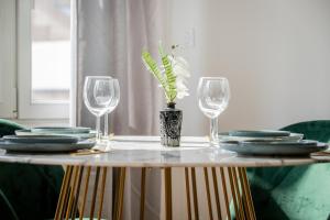 a table with glasses and a vase with a plant on it at Perle de Liévin in Liévin