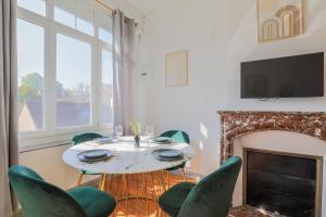 a dining room with a table and chairs and a fireplace at Perle de Liévin in Liévin