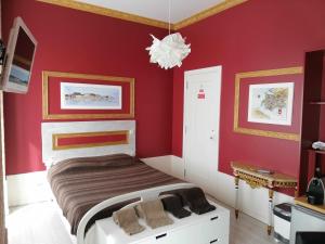 a bedroom with a bed with red walls and a chandelier at Legendary Bay - Suíte Temática in Seixal