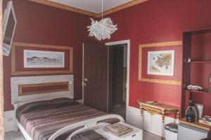 a bedroom with red walls and a bed with a chandelier at Legendary Bay - Suíte Temática in Seixal