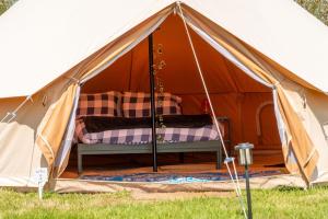 a tent with a bed in it in the grass at Boscoppa Farm-Furnished Bell Tent 4 in St Austell