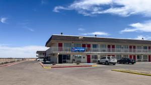 a hotel with cars parked in a parking lot at Motel 6 - Pecos, TX in Pecos