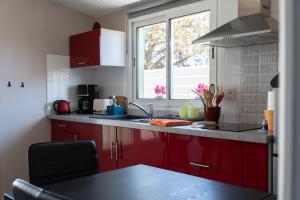 a kitchen with red cabinets and a sink and a window at Le Marsalat - Lanton in Lanton