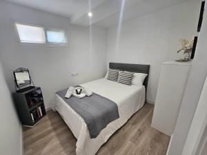 a white bedroom with a bed with a gray blanket at El capricho in Fuengirola