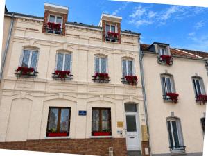 a building with red flowers in the windows at La Petalerie Appartements d'hôtes in Épernay