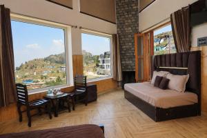 a bedroom with a bed and a table and windows at Hotel Amadeus in Kanatal
