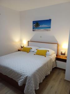 a bedroom with a white bed with two yellow pillows at Apartments Jure Miljak in Podstrana