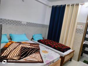 two beds in a room with blue curtains at Hotel suryoday kharadi in Barkot