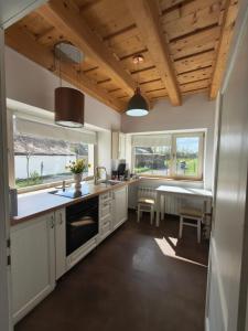 a kitchen with white cabinets and a table and two windows at Casa Via Viscri in Buneşti