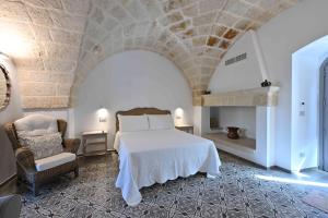 a bedroom with a white bed and a chair at Corte di Torre Spaccata in Torre Canne +59 photos