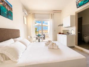 a white bedroom with a large white bed and a kitchen at RestHouse The Village in Nardò