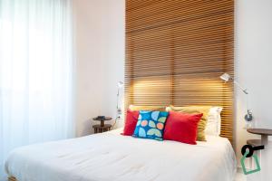 a bedroom with a white bed with a wooden headboard at Hotiday Torre Lapillo Centro in Torre Lapillo