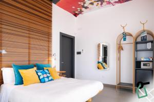 a bedroom with a white bed with blue and yellow pillows at Hotiday Torre Lapillo Centro in Torre Lapillo