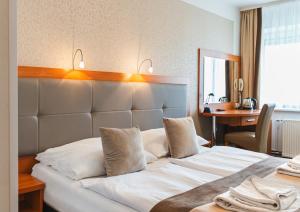 a hotel room with a large white bed and a desk at Hotel ARA - Dancing Club Restauracja Kameralne SPA ARA in Jastrzębia Góra +42 photos