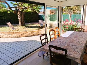 a table and chairs on a porch with a table and a window at La Pause Jardaise in Jard-sur-Mer
