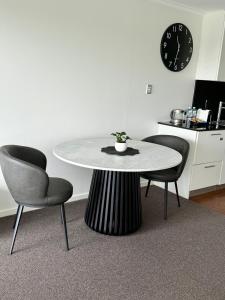 a table and two chairs in a room with a clock at HAVEN by the Sea in Mandurah