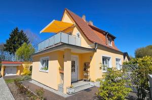 a yellow house with a balcony on top of it at Haus Richard in Ahlbeck