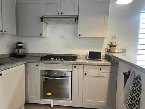 a kitchen with white cabinets and a stove top oven at Calm Stay Monte Plata in Monte Plata +14 photos