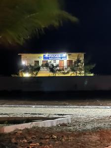a building with a sign on the side of it at night at Pousada Recanto do Marinheiro in Aracati