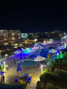 a swimming pool with tables and umbrellas at night at Lasirena in Ain Sokhna +11 photos