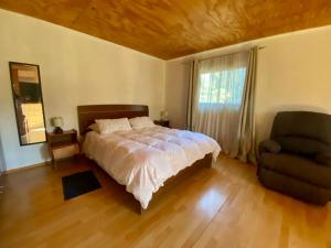 a bedroom with a bed and a chair and a window at Refugio Escondido in Isla de Maipo