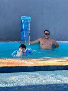 a man and a child in a swimming pool at Pousada Recanto do Marinheiro in Aracati