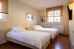 two beds in a room with two windows at Port-Grimaud - La Maisonnette - sur plage et front de mer in Grimaud