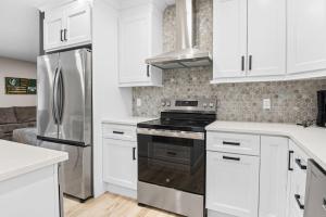 a kitchen with white cabinets and a stainless steel refrigerator at Good Lodge - Hot Tub Beach Access Pool Table in Lake Harmony +47 photos