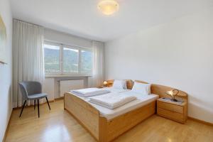 a bedroom with a bed with a chair and a window at Ferienappartement Freiblick in Marlengo