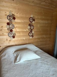 a bed in a room with a wooden wall with clocks at Chalet in Fleury-sur-Loire