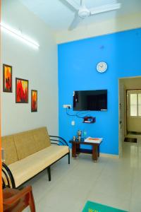 a living room with a couch and a blue wall at Arun Lodge and Cottage Near Thiruchendur in Korkai +19 photos