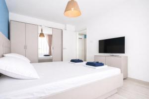 a white bedroom with a large white bed and a flat screen tv at Апартамент Tiana 2 in Tsarevo