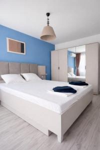 a large white bed in a bedroom with a blue wall at Апартамент Tiana 2 in Tsarevo