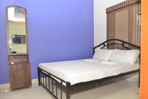a bed in a room with a blue wall and a mirror at Arun Lodge and Cottage Near Thiruchendur in Korkai