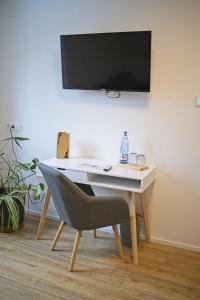 a desk with a chair and a television on a wall at Haus RAuszeit in Wildemann