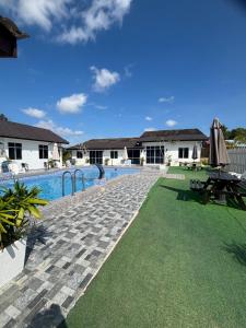 a swimming pool with a stone walkway next to a house at D' Ehsan Homestay & Chalet in Kuala Terengganu