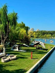 a park with tents on the grass next to a river at BeiJing Seeyou Youth Hostel Adjacent to Yonghe Temple and Sanlitun, with direct access to the airport in Beijing