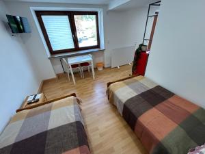 zwei Betten in einem Zimmer mit einem Tisch und einem Fenster in der Unterkunft Werkblick in Niederaigen