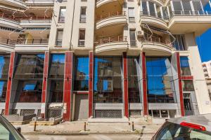 a tall building with glass windows on a street at Love in Colours by PikHost in Durrës