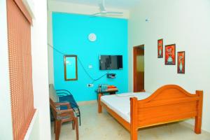 a bedroom with a bed and a blue wall at Arun Lodge and Cottage Near Thiruchendur in Korkai