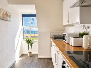 a kitchen with white cabinets and a window at Marine Parade - Beach Apartment in Southtown