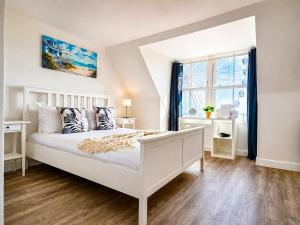 a white bedroom with a large bed and a window at Marine Parade - Beach Apartment in Southtown